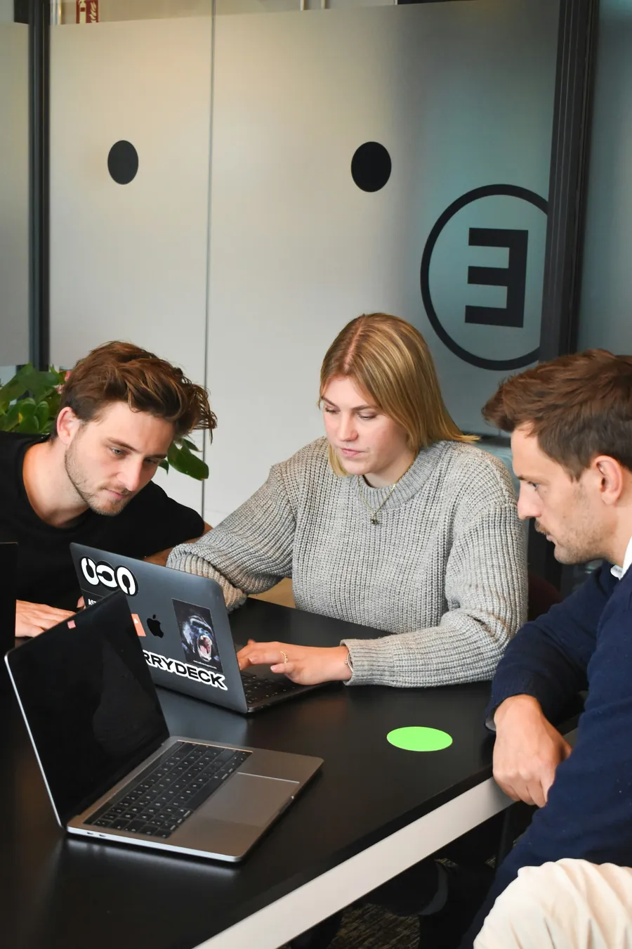 Drei Personen arbeiten gemeinsam an einem Laptop
